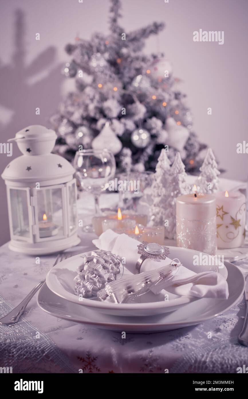 Festlicher Weihnachtstisch mit Besteck, Kerzen und dekoriertem Weihnachtsbaum Stockfoto