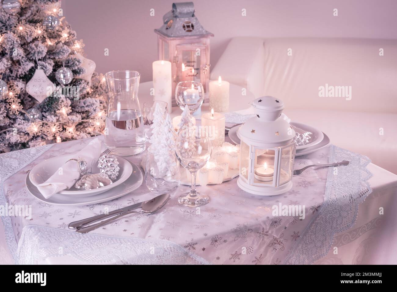 Festlicher Weihnachtstisch mit Besteck, Kerzen und dekoriertem Weihnachtsbaum Stockfoto