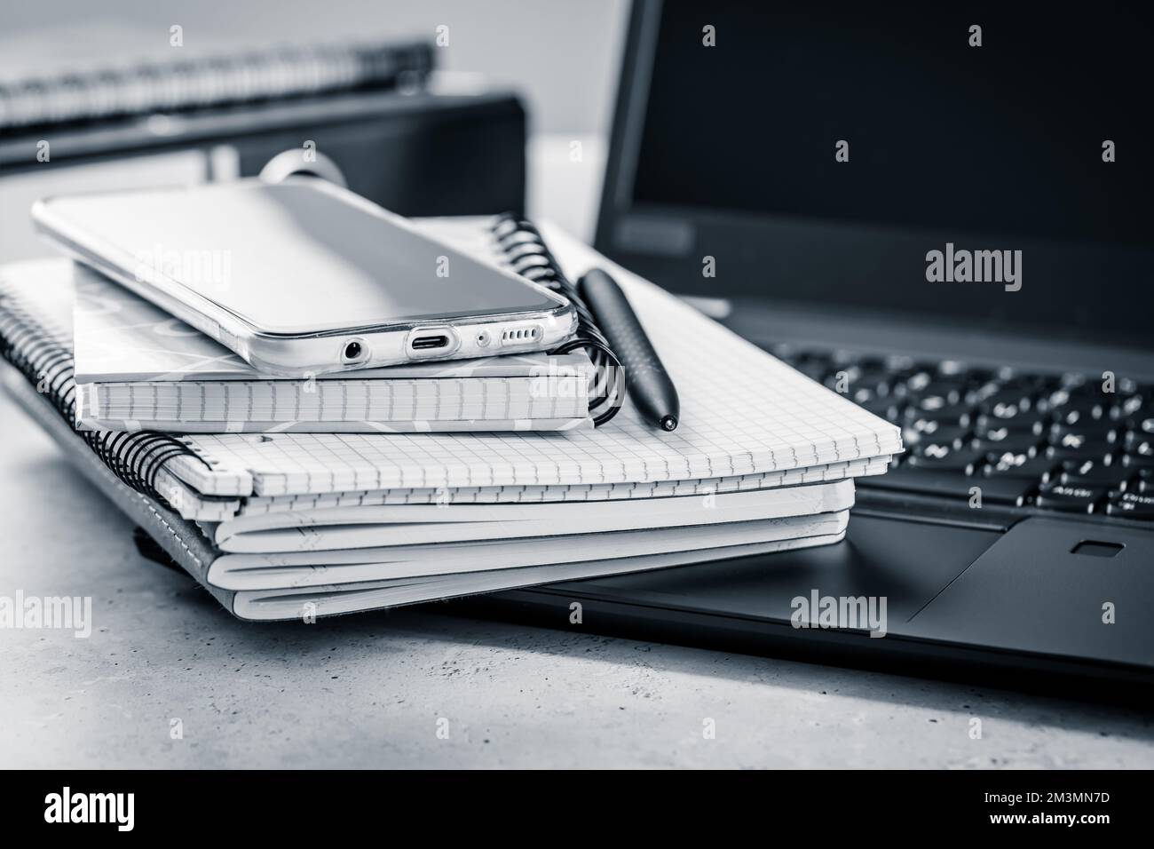 Bürotisch – Stapel von Notebooks, Mobiltelefon mit Laptop Stockfoto
