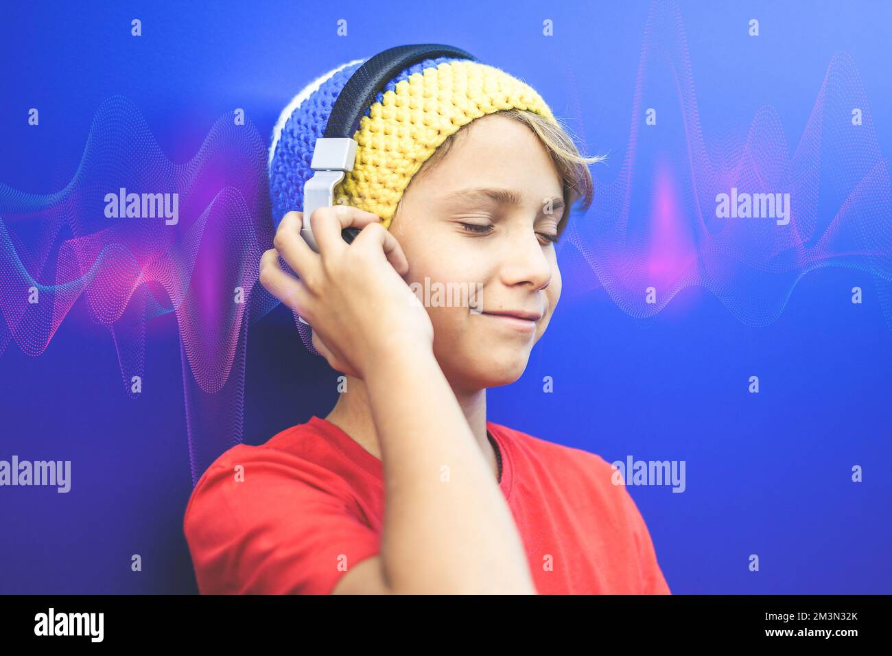 Fröhliches Lächeln beim Musikhören mit Kopfhörern. Schallwellen auf blauem Hintergrund. Stockfoto