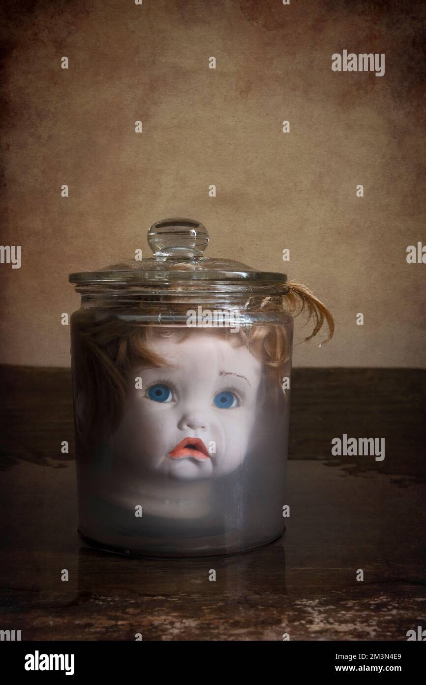 Ein unheimlicher Puppenkopf in einem Glas Wasser. Stockfoto