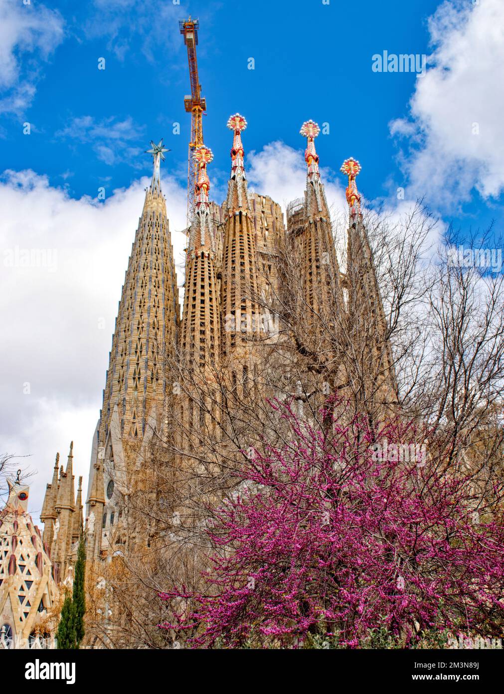 Basílica i Tempel Expiatori de la Sagrada Família und ein großer gelber Kran während des Baus der bunten Türme Stockfoto