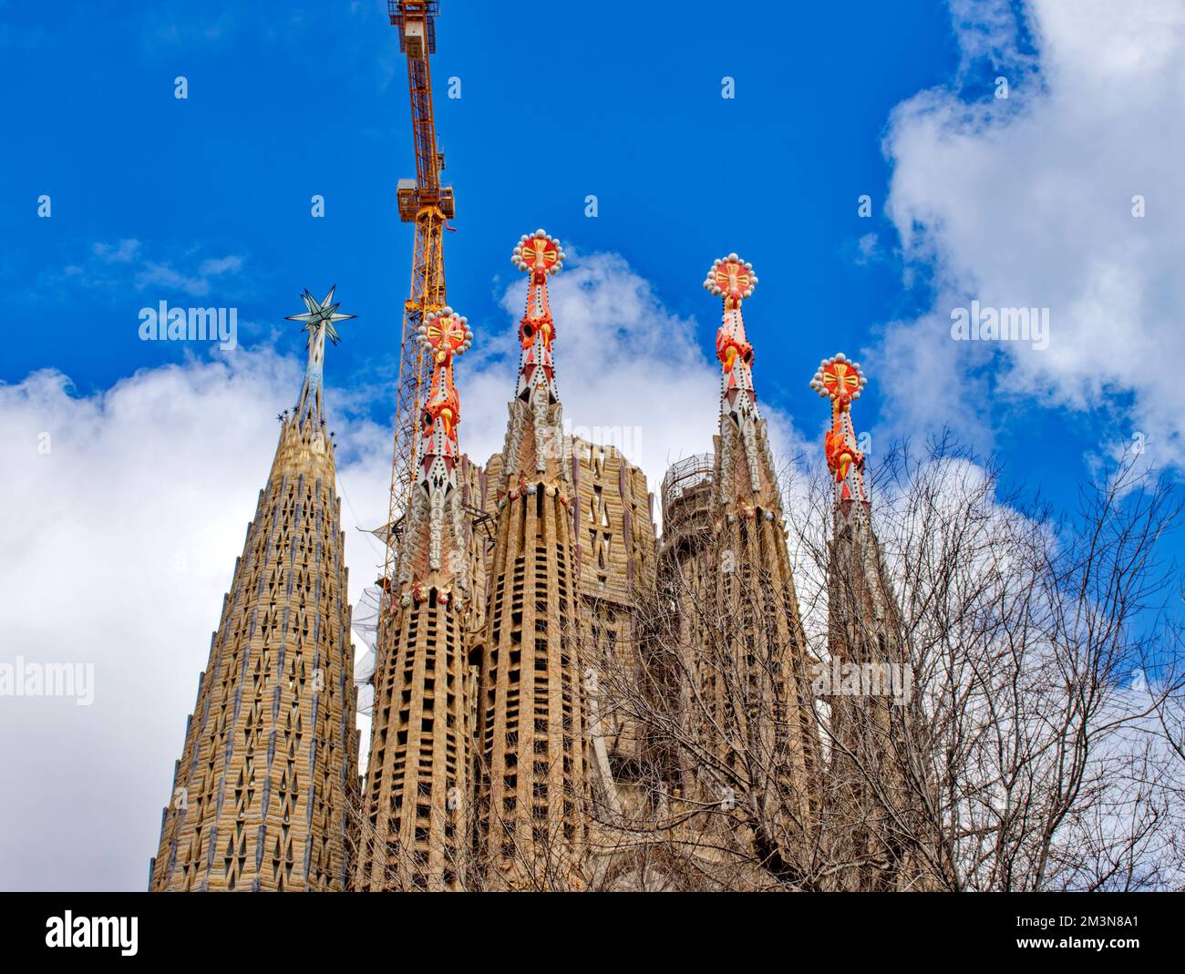 Basílica i Tempel Expiatori de la Sagrada Família und gelber Kran während des Baus der bunten Türme Stockfoto