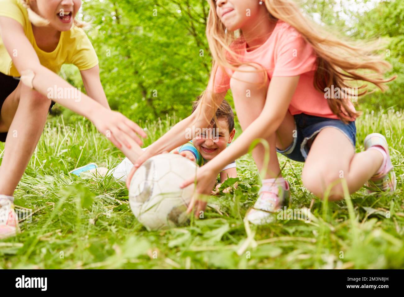Mädchen, die mit einem männlichen Freund während des Wettkampfs im Park Fußball spielen Stockfoto