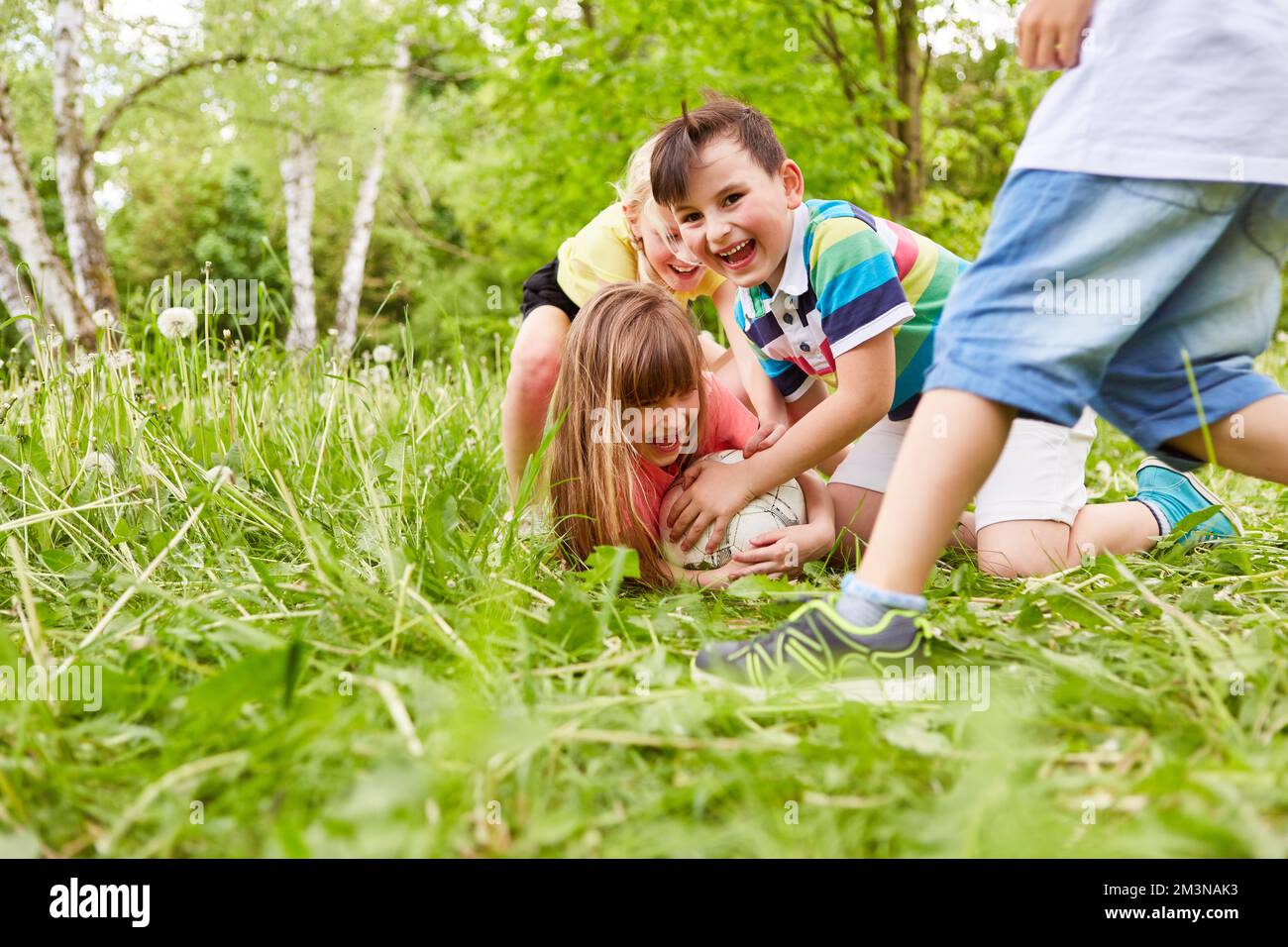 Eine Gruppe von Kindern, die Fußball spielen und im Gras Fußball spielen Stockfoto
