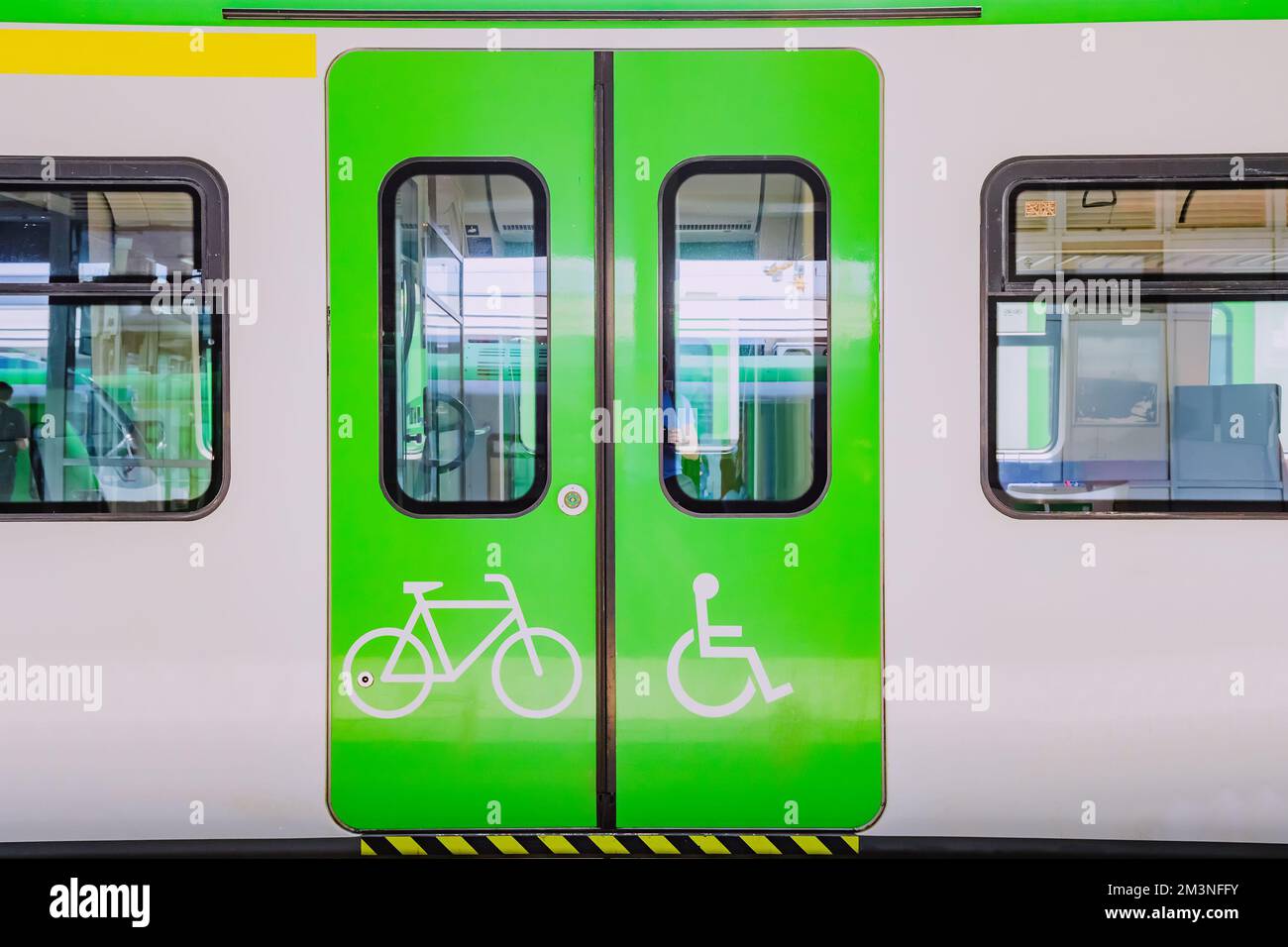 Die Beförderung eines modernen elektrischen Zuges zur Beförderung von Fahrgästen mit Rollstuhl- und Fahrradsymbolen. Konzept der Barrierefreiheit Stockfoto