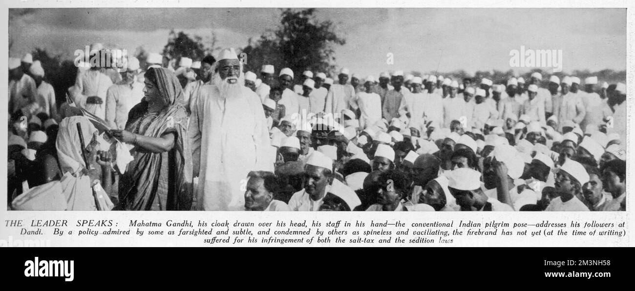 Mahatma Gandhi, sein Umhang über seinem Kopf, sein Stab in der Hand, spricht mit seinen Anhängern in Dandi zum Höhepunkt des Salzmarsches oder Satyagraha, einem Massenprotest des zivilen Ungehorsams gegen die britische Salzsteuer. Datum: April 1930 Stockfoto