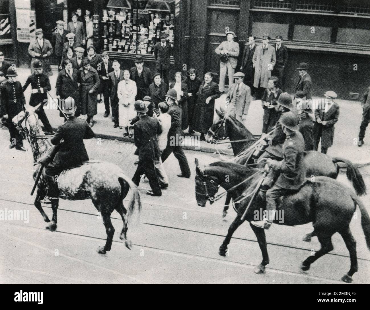 Die Polizei nimmt einen Mann fest und eskortiert ihn weg, umgeben von berittener Polizei. 84 Festnahmen wurden während der antifaschistischen Demonstration gegen den von Sir Oswald Mosley und der britischen Faschistenunion vorgeschlagenen marsch im East End von London verübt. Die faschistische Prozession wurde entlang des Ufers umgeleitet. Datum: 4. Oktober 1936 Stockfoto