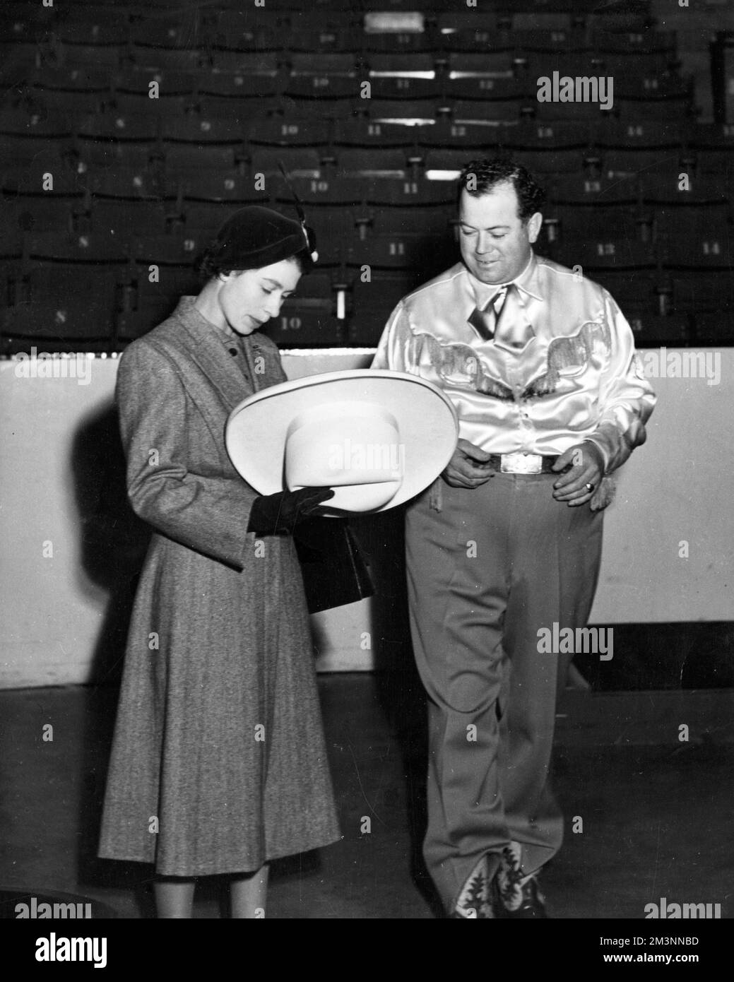 Der Bürgermeister von Calgary (Alberta), Herr Don Mackay, zeigt Prinzessin Elizabeth einen „zehn Gallonen“-Hut, als ihre Königliche Hoheit und der Herzog von Edinburgh (der mit einem „zehn Gallonen“-Hut präsentiert wurde und diesen trug) Calgary besuchten, um ein Rodeo im Stadion zu besuchen. Datum: 1951 Stockfoto