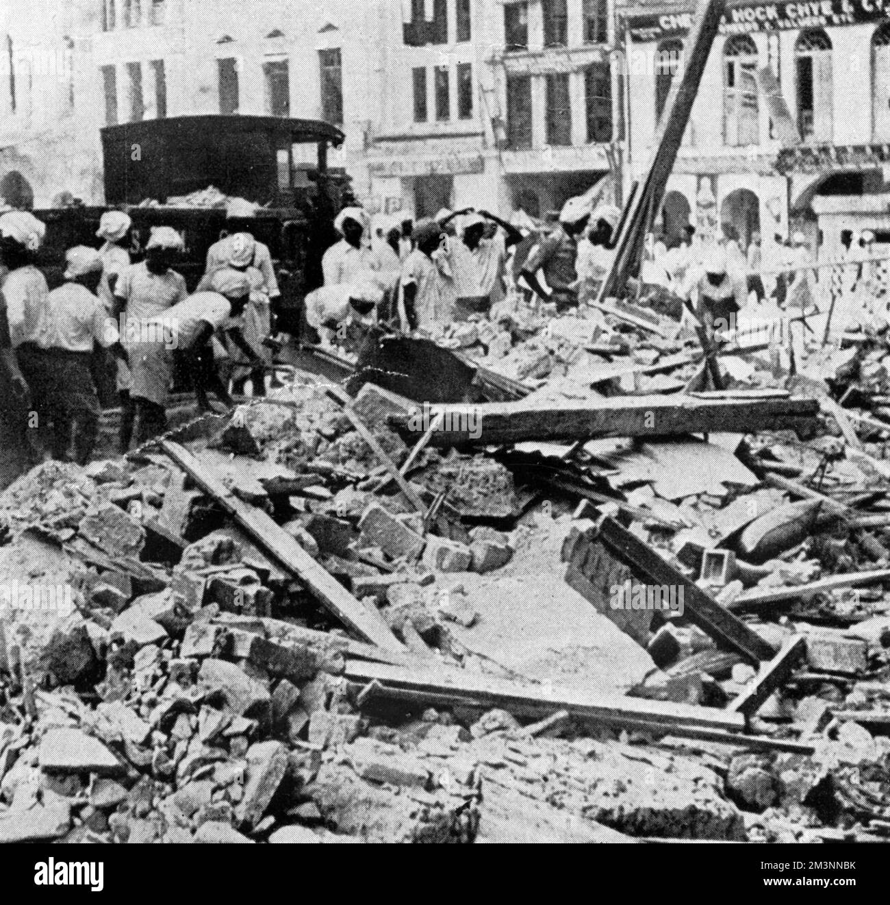 Einwohner Singapurs schätzen den Schaden ein, den ein japanischer Luftangriff in der Nacht zuvor verursacht hat. Datum: Januar 1942 Stockfoto