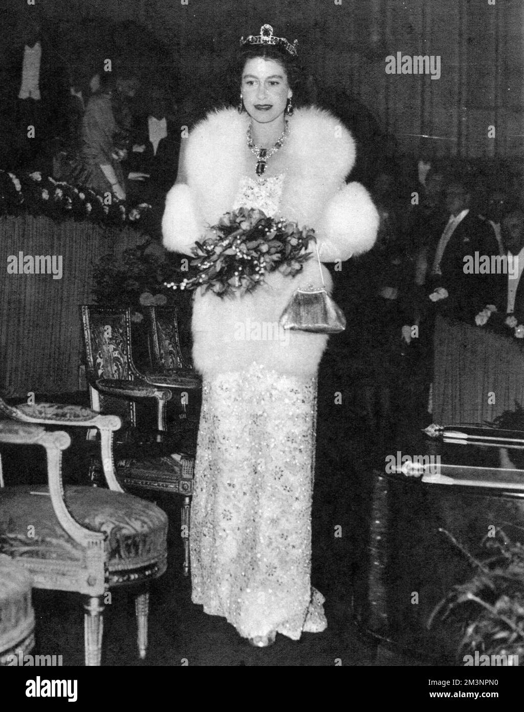 Königin Elizabeth II. Sieht opulent aus in einem perlenbesetzten Abendkleid und Pelzmantel. Die Veranstaltung war die Royal Film Performance im Odeon Theatre am Leicester Square, London. Datum: 1957 Stockfoto
