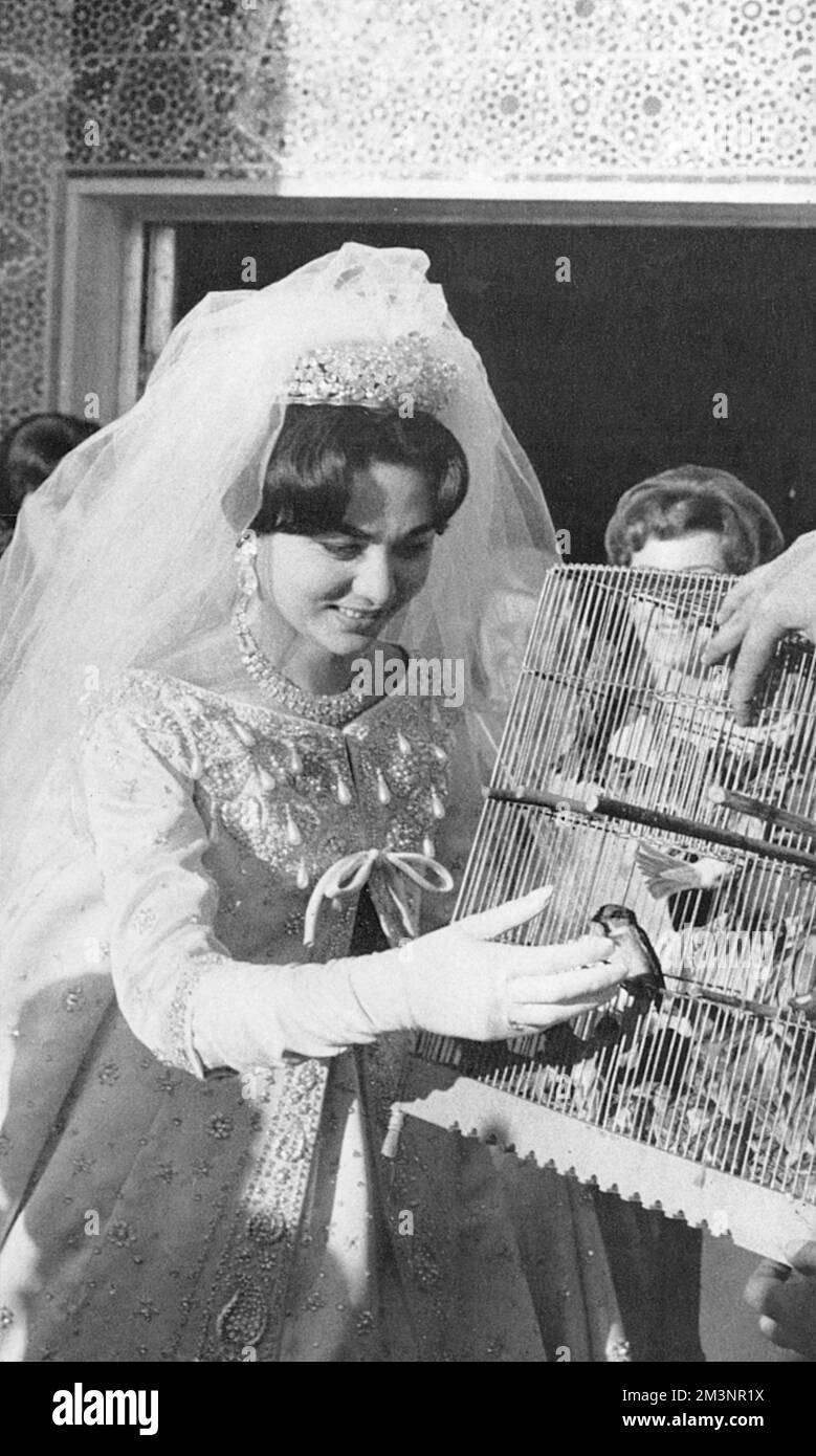 Farah Diba (geboren 1938), dritte Ehefrau von Mohammad Reza Pahlavi, letzter Schah von Persien (Iran), die am Tag ihrer Hochzeit einige Vögel in Käfigen symbolisch freiließ, in einem Kleid von Christian Dior. Datum: 1960 Stockfoto