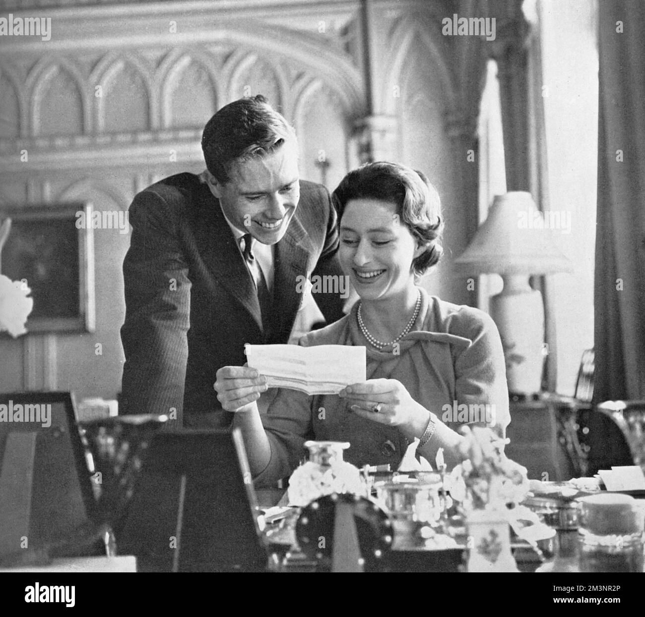 Prinzessin Margaret (1930 - 2002) und ihr Verlobter Antony Armstrong-Jones (Lord Snowdon) lesen Telegramme mit guten Wünschen, die nach der Ankündigung ihrer Verlobung gesendet wurden. Datum: 1960 Stockfoto