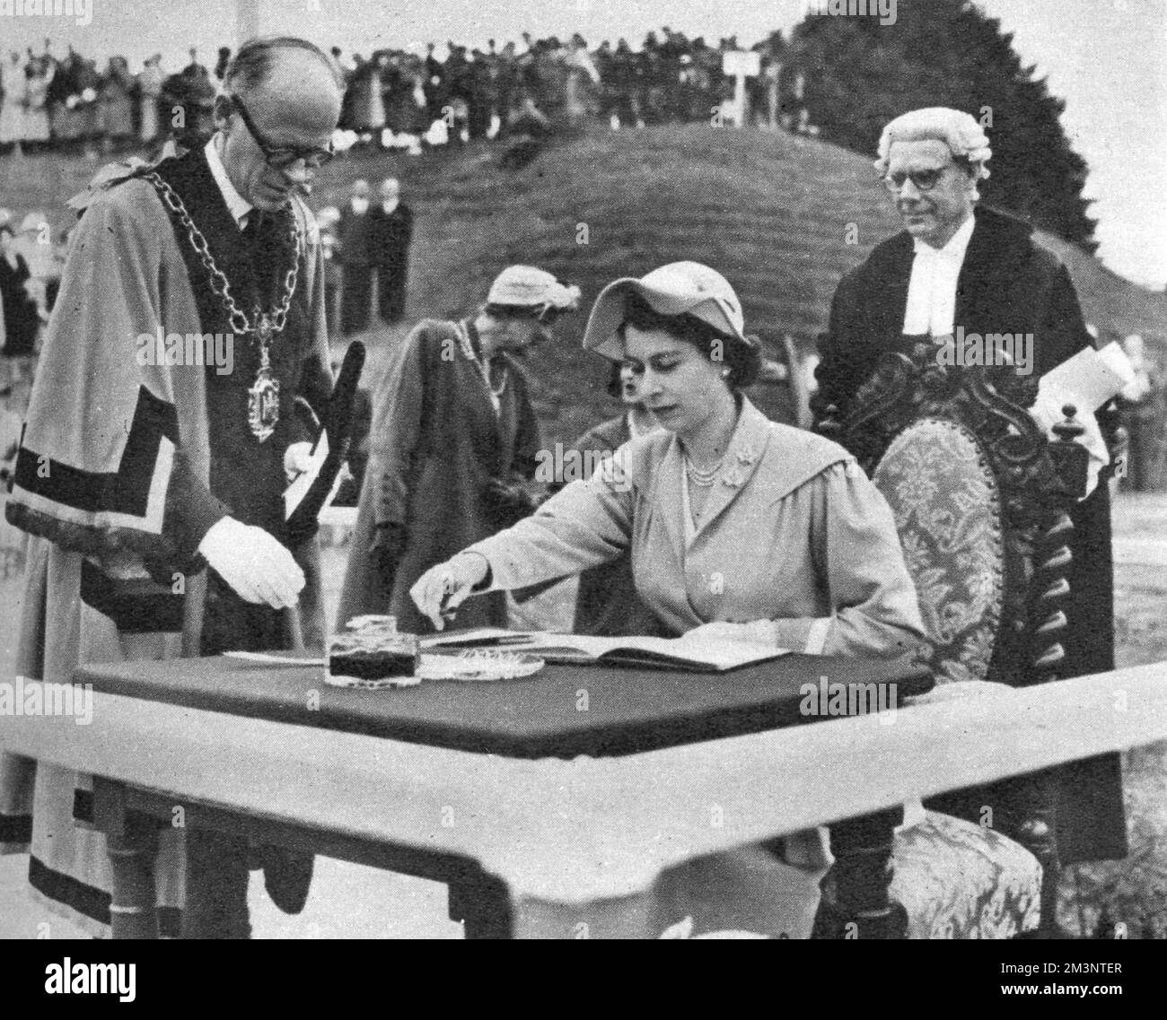 Königin Elisabeth II. Unterzeichnet das berühmte Besucherbuch bei Maumbury Rings in Dorchester, Dorset, einem jungsteinzeitlichen Rundbauwerk, das später als römisches Amphitheater umgebaut wurde. Sie hat gerade eine Adresse vom Bürgermeister von Dorchester erhalten. Datum: 3.. Juli 1952 Stockfoto