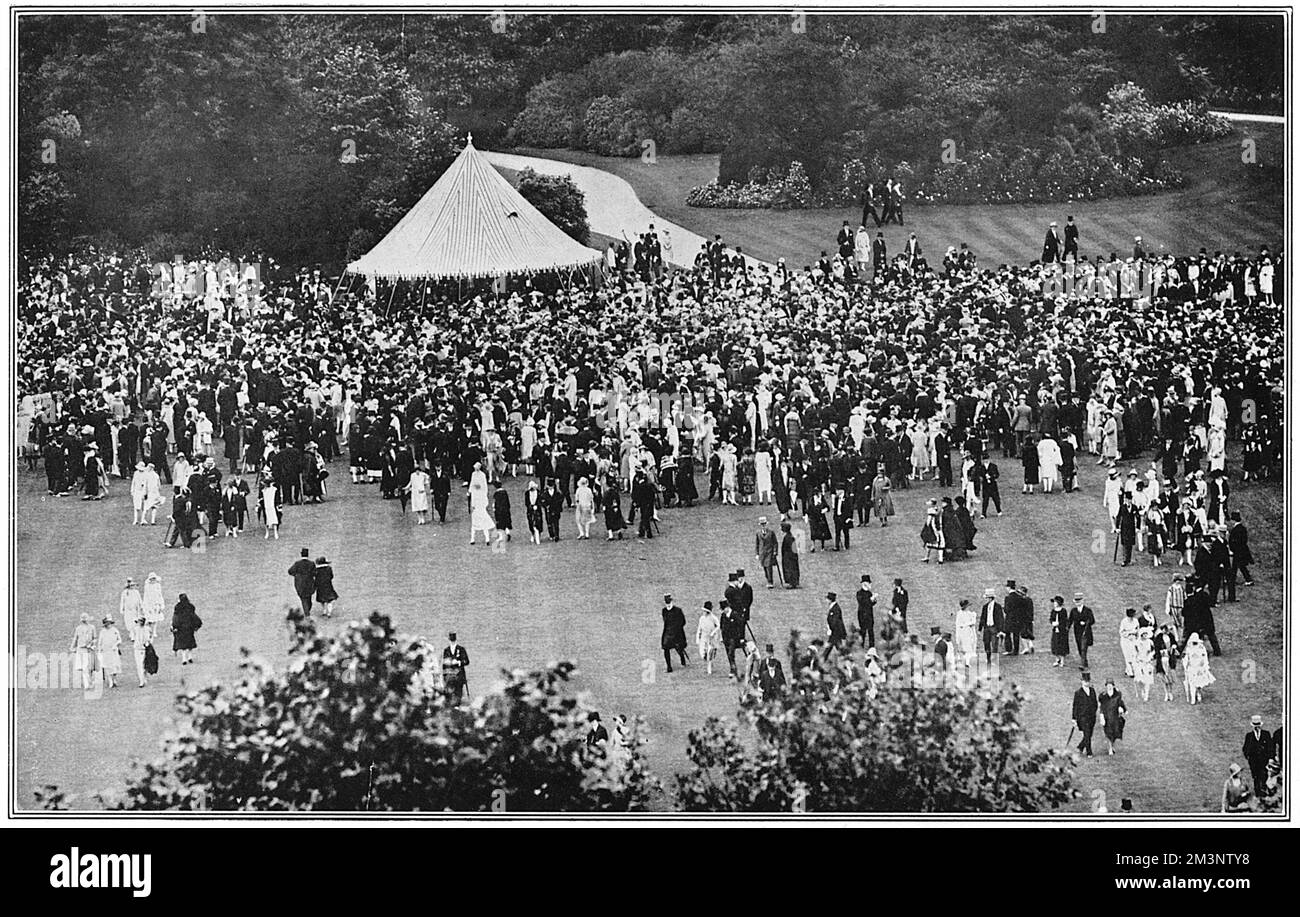 Ein Panoramablick auf eine große Anzahl von Gästen, die auf dem Gelände des Buckingham Palace bei einer Garden Party von König George V. und Königin Mary im Jahr 1927 spazieren gehen. Datum: 1927 Stockfoto