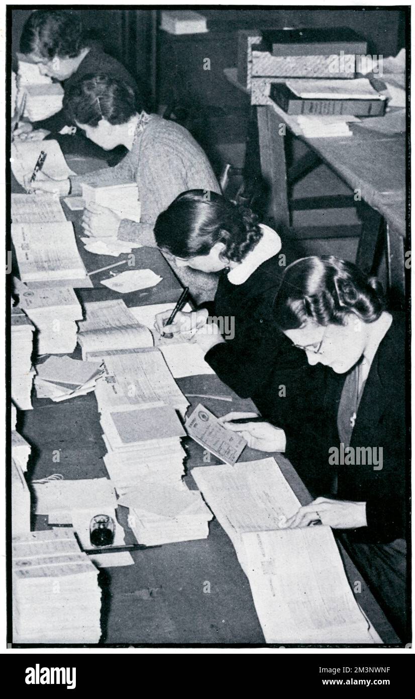 Mädchen, die damit beschäftigt waren, die Rationsbücher mit Namen und anderen Informationen auszufüllen, bevor sie 1939 an die britische Bevölkerung verteilt wurden. Datum: 1939 Stockfoto