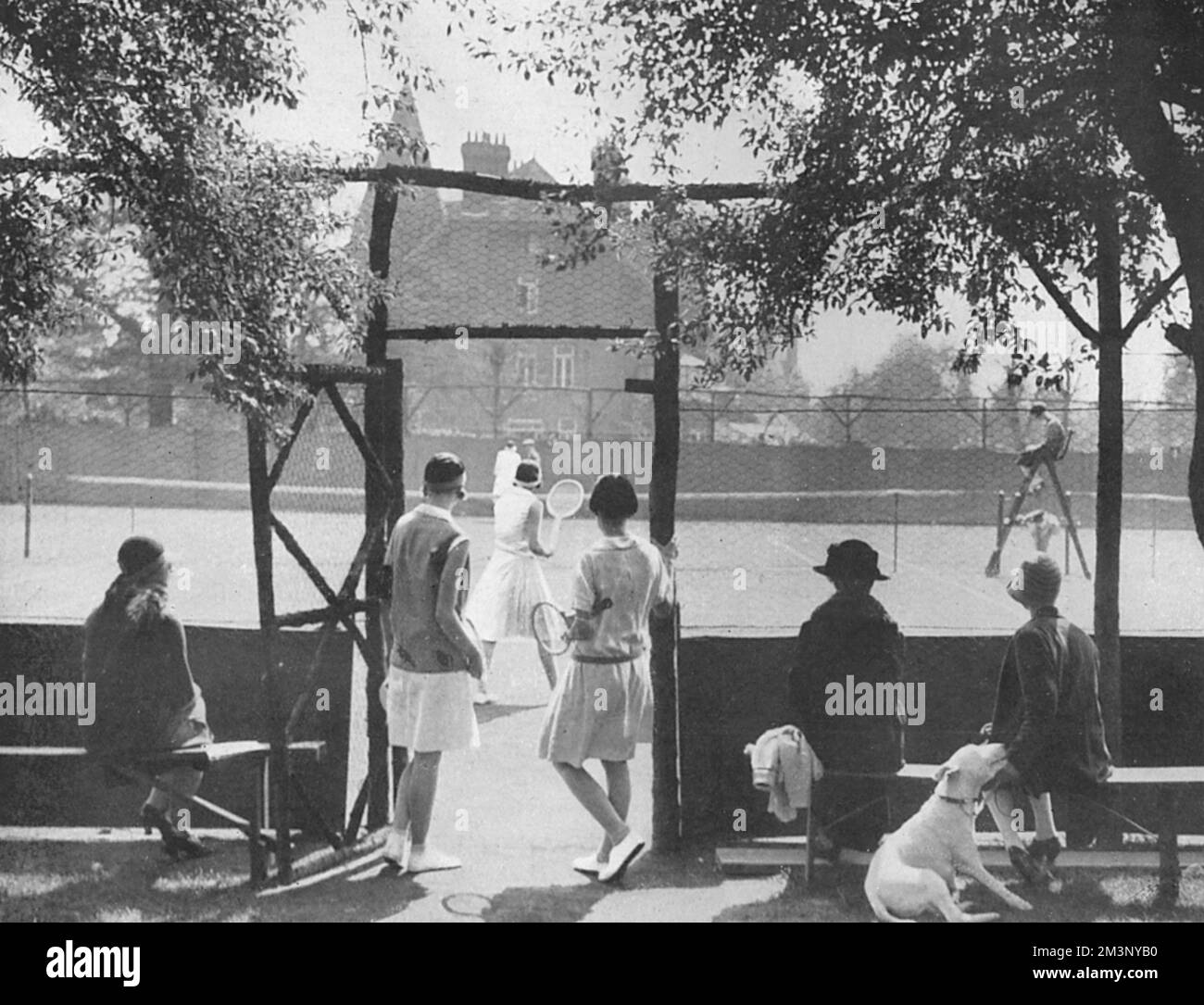 Malerischer Blick auf die Tennisplätze im West Side Country Club in Ealing mit Zuschauern und Wettbewerbern, die spielen. Datum: 1928 Stockfoto