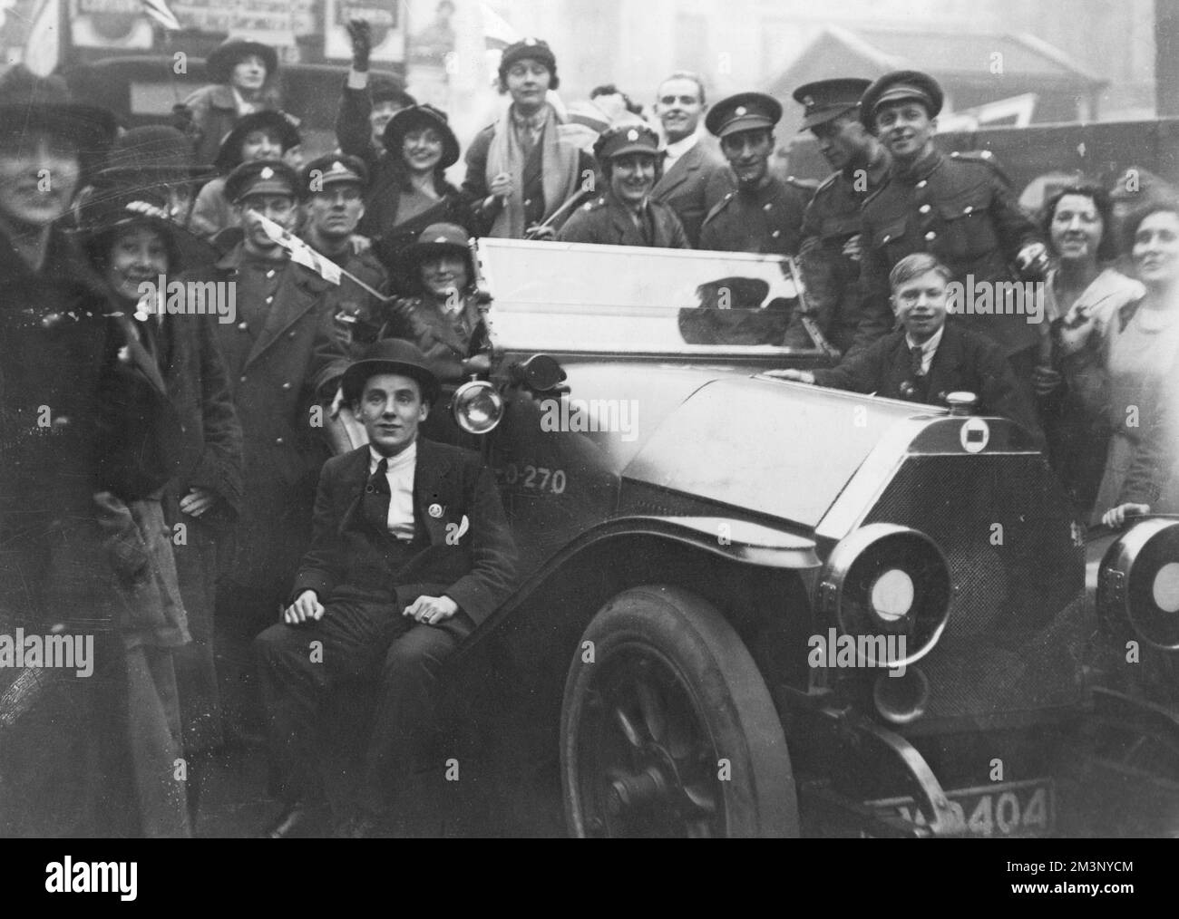 Eine glückliche Menschenmenge von Männern und Frauen, einige in Militäruniform, andere in Zivilisten, in London am Waffenstillstandstag, 11.. November 1918, um ein Auto herum. Datum: 11.. November 1918 Stockfoto
