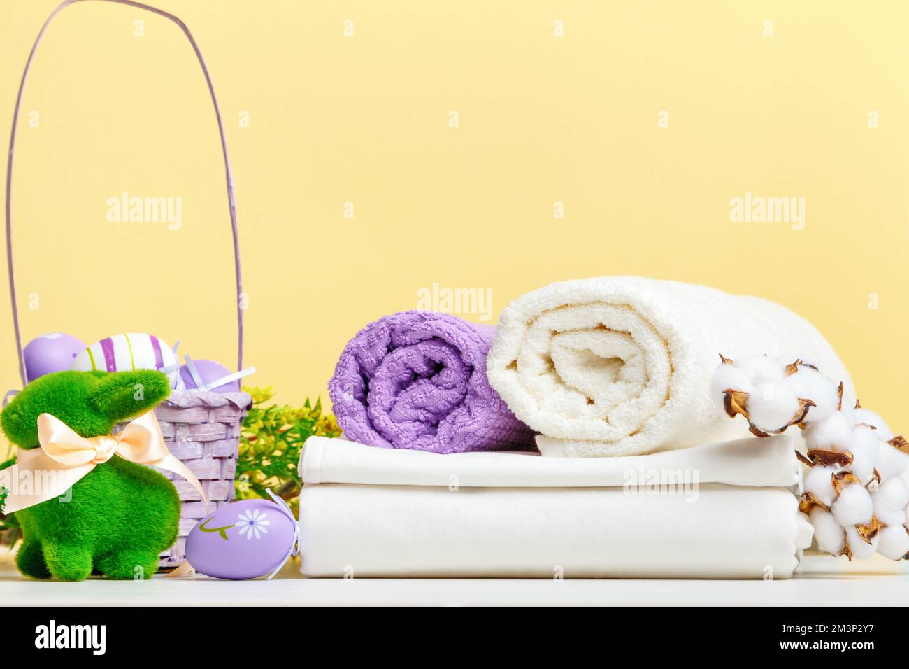 Handtuchrollen, weiße Bettwäsche und osterdekoration auf dem Tisch Stockfoto
