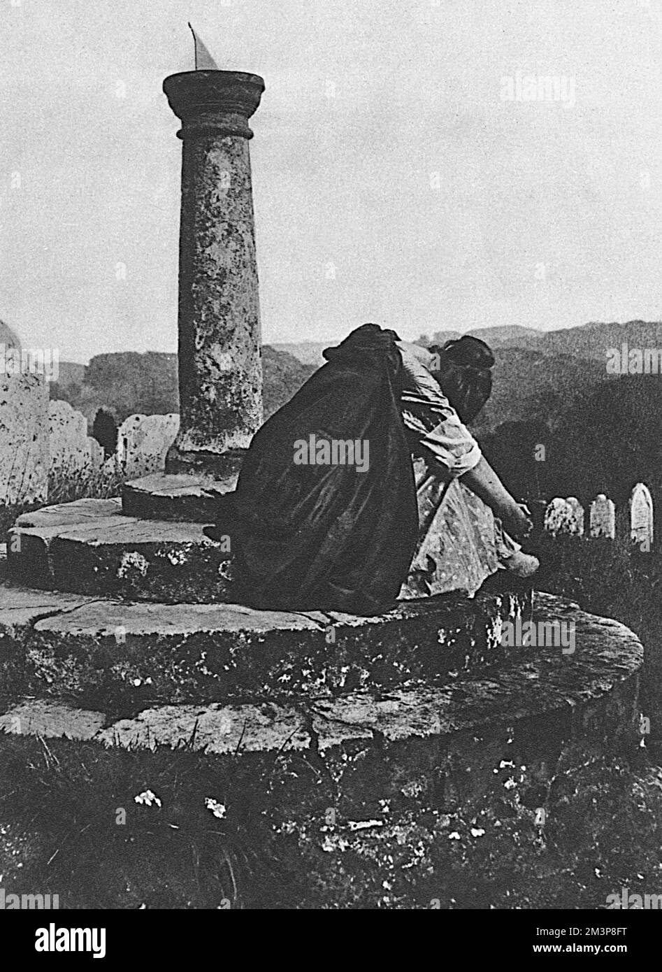 Eine Kriegswitwe aus der Zeit des Großen Krieges sitzt weinend an einer Sonnenuhr auf einem Friedhof. Das Bild auf der vorherigen Seite (Bild Nr. 10700921) stellt eine Kriegsbraut dar, eine künstlerische Darstellung der oft flüchtigen Eheschließungszeit, die frisch Vermählte während des Ersten Weltkriegs genossen. Datum: 1915 Stockfoto