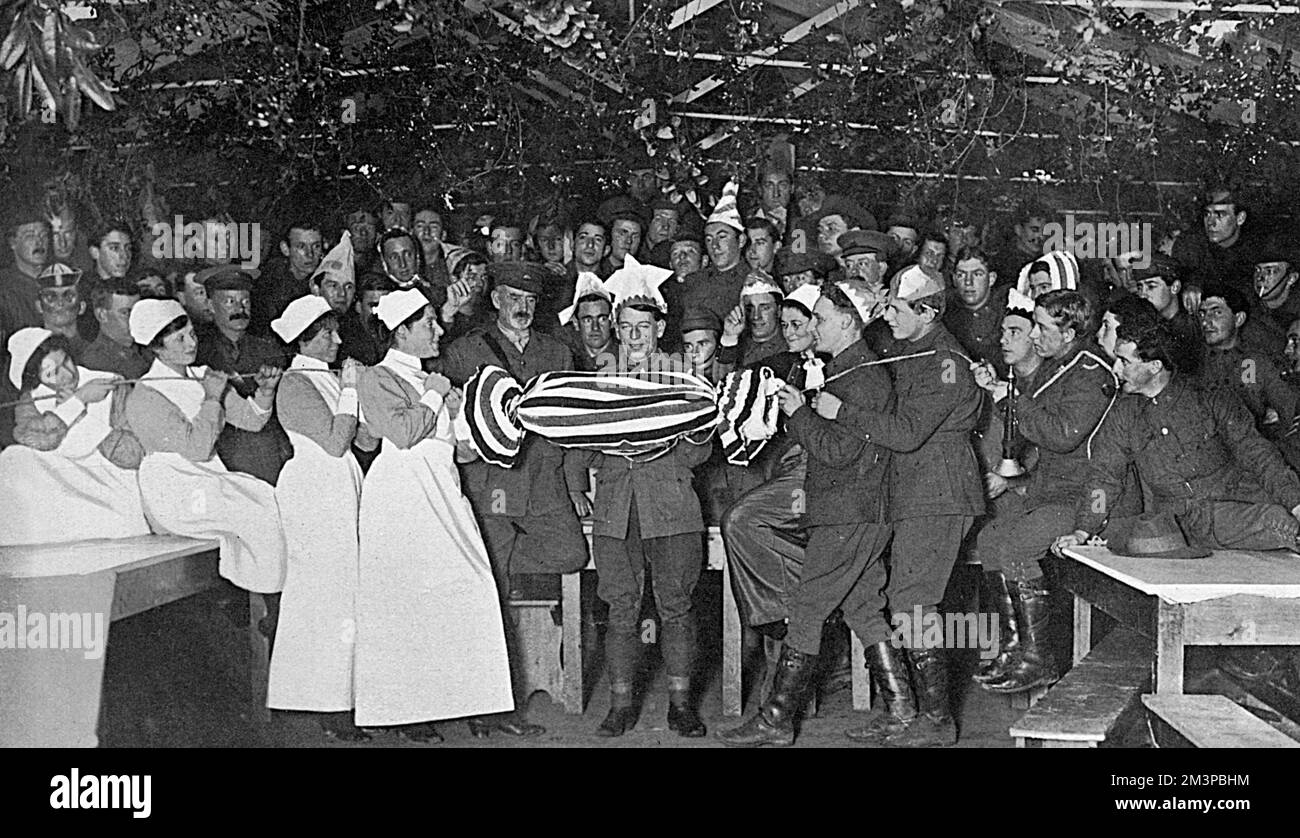 Verwundete australische Soldaten wurden am ersten Weihnachtsfeiertag im Dezember 1916 im Harefield Park in traditionellem Stil unterhalten. Ein Mann gegen Frau kämpft um die Öffnung eines riesigen Weihnachtsknicks und die zweite Figur von links ist Miss Birdwood, Tochter von Lieut.-Gneral Sir William Birdwood, bekannt als Befehlshaber der australischen und neuseeländischen Truppen in Gallipoli im Jahr 1915. Datum: 1916 Stockfoto