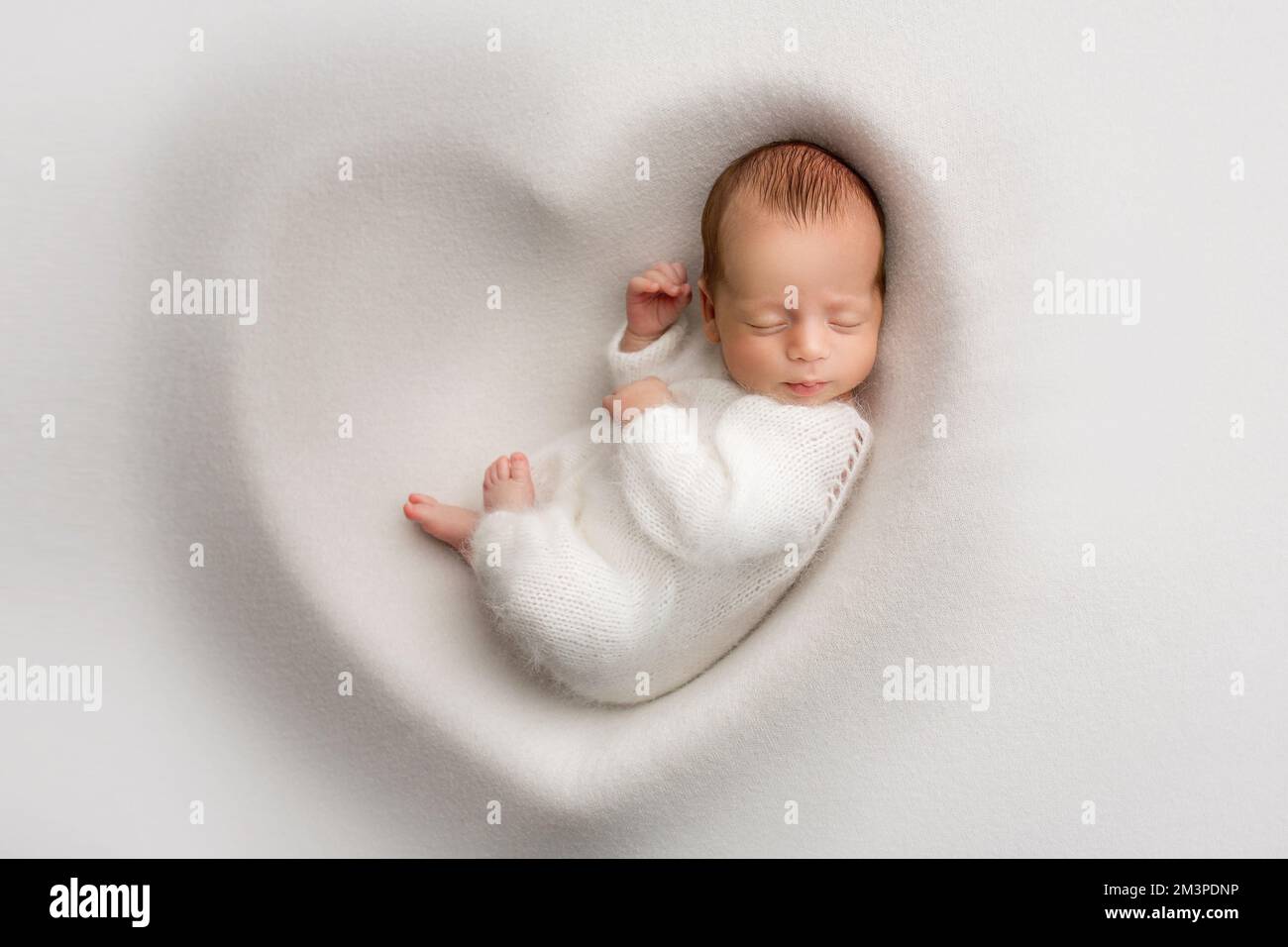 Ein schlafender Neugeborener in den ersten Lebenstagen in einem weißen, weichen Kokon Stockfoto