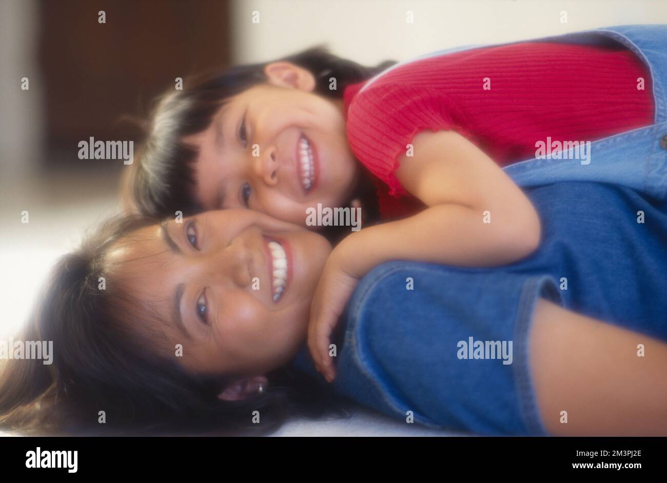 Asiatische Mutter und Tochter spielen. Ein kleines Mädchen, das auf seiner Mutter liegt Stockfoto