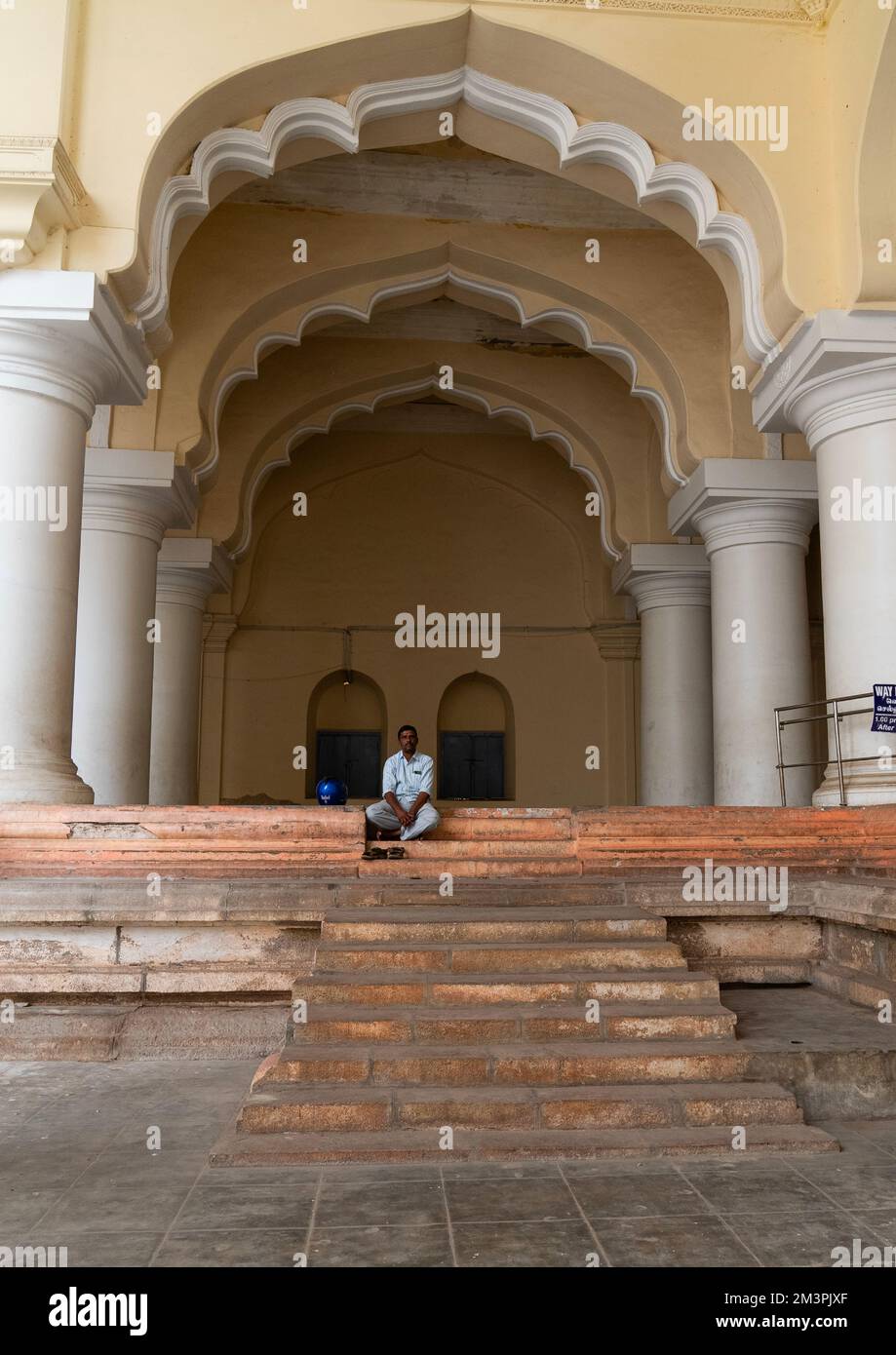 Der Mann sitzt in der Säulenhalle des Thirumalai Nayakar Palastes, Tamil Nadu, Madurai, Indien Stockfoto