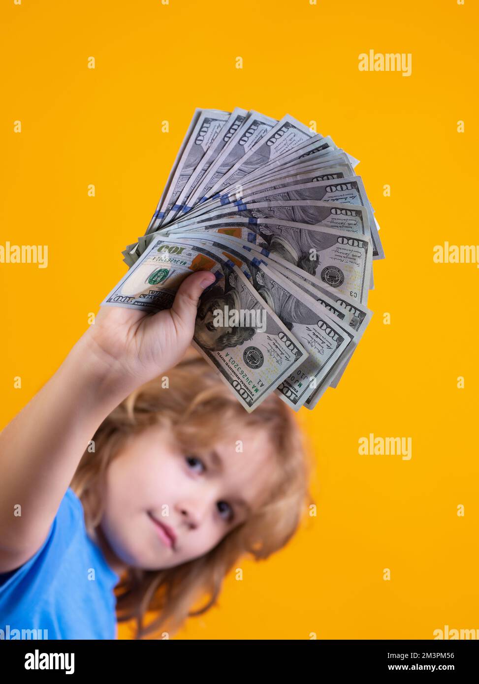 Das Kind hat viele hundert Dollar isoliert auf gelbem Hintergrund. Stockfoto