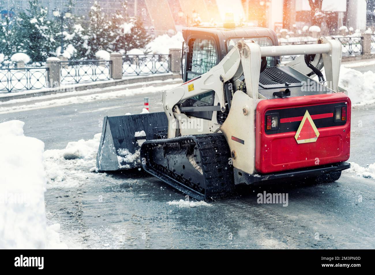 Skistraktoren-Ladermaschine reinigen schmutzigen Schnee auf der Fahrbahn. Die Straßen der Stadt säubern, Schneeeis bei schweren Schneefällen und Schneestürmen entfernen. Schneepflug Stockfoto