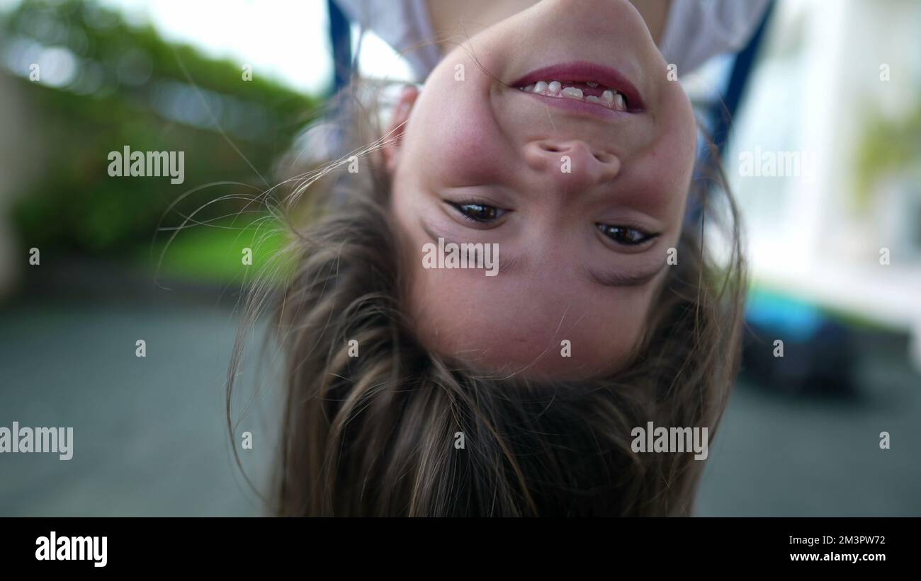 Ein sorgenfreies kleines Mädchen, das kopfüber auf dem Spielplatz hängt, spielt in der Affenbar und genießt den Sommer Stockfoto