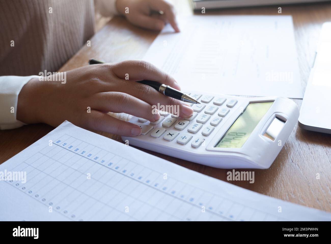 Zugeschnittenes Bild einer professionellen Geschäftsfrau, Unternehmerin oder Buchhalterin, die an ihrem Schreibtisch mit einem Taschenrechner oder Laptop an einem Finanzbericht arbeitet Stockfoto