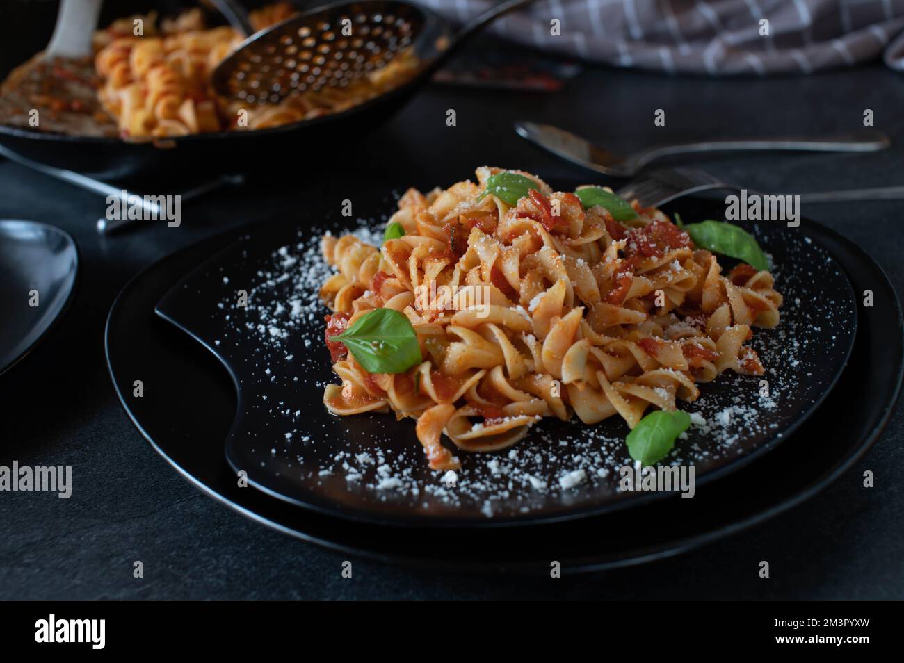 Pasta mit Tomatensauce und Parmesankäse. Mit Fusilli-Nudeln zubereitet und auf einem dunklen Teller serviert Stockfoto