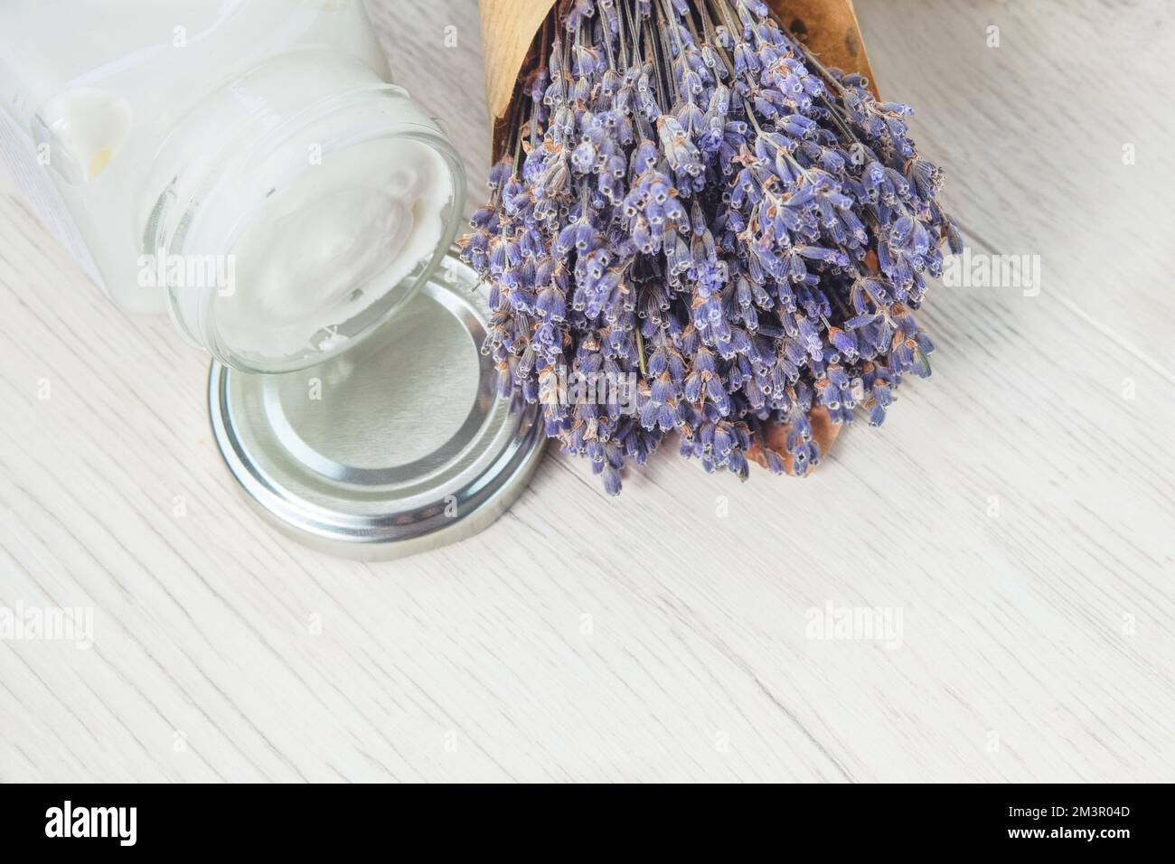Handgefertigte kosmetische Cremebecher und getrocknete Lavendelblumen auf hellem Hintergrund. Ganzheitliche Kosmetik. Stockfoto