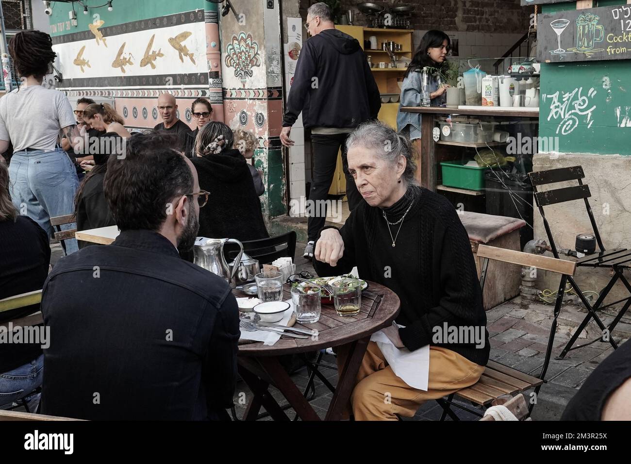 Tel Aviv, Israel. 16.. Dezember 2022. Sitzplätze im Freien im Café Yom Tov auf dem Shuk HaCarmel Market, einem Außenmarkt, der in t Stockfoto