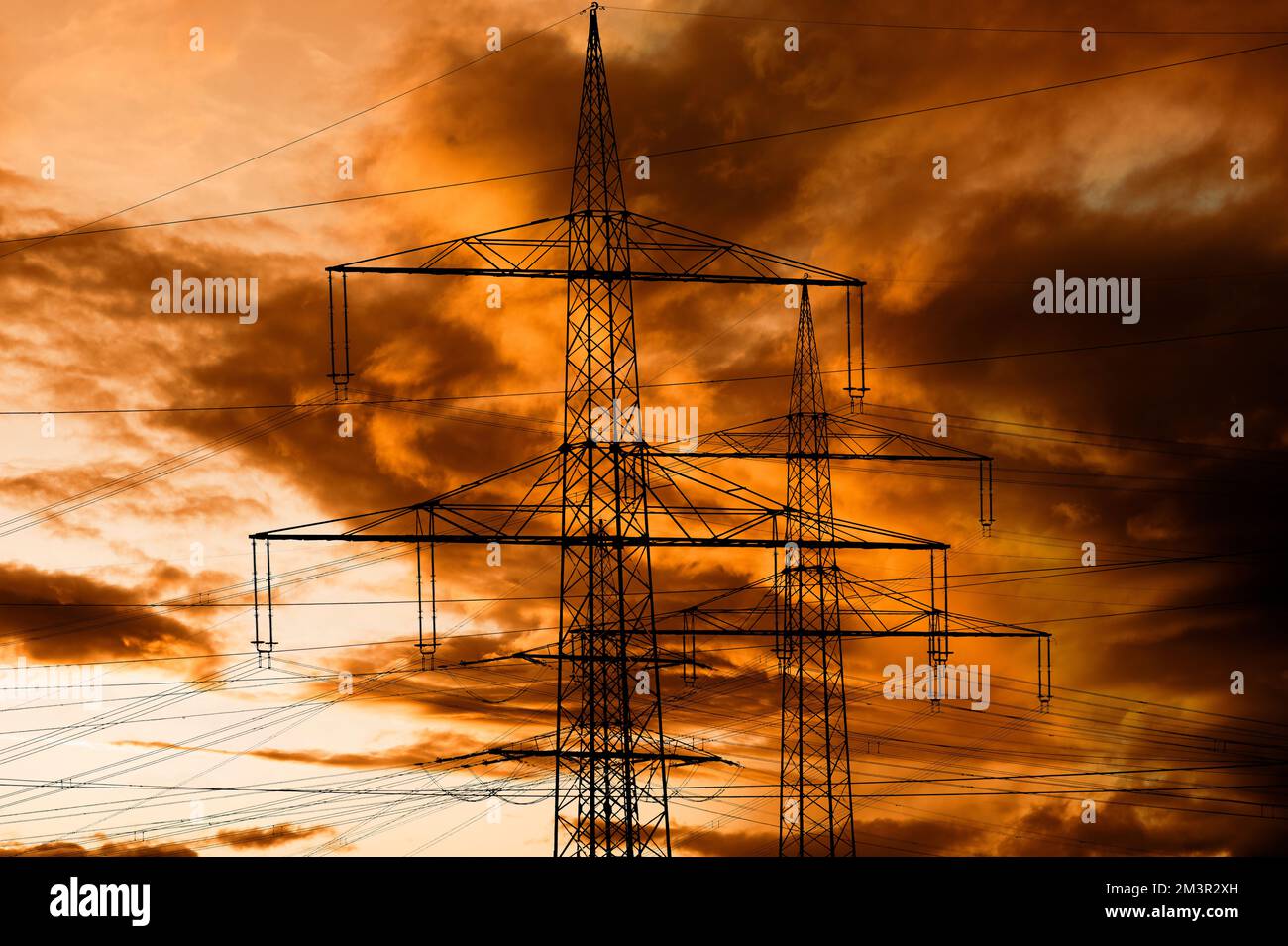 Hochspannungsmasten für Elektrizität und Kraft gegen den Himmel mit dramatischen Wolken Stockfoto