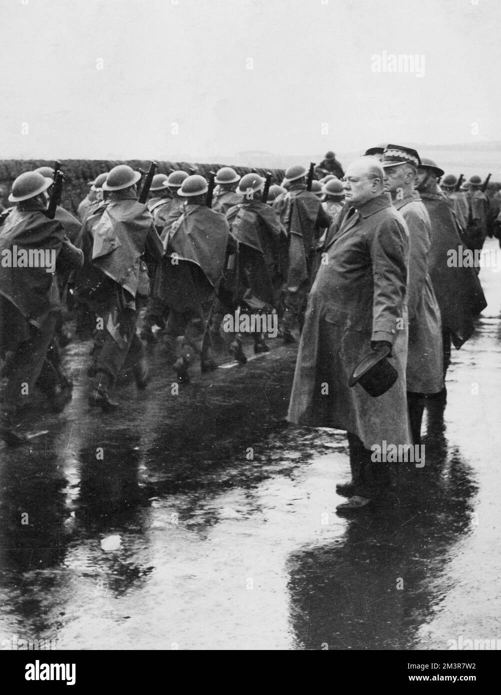 Herr Winston Churchill, trotz des Regens in der Hand, beobachtet eine marschzeit der Truppen während seines Besuchs in den Küstenbezirken Ostschottlands, wo er weitere britische Verteidigungssysteme inspizierte. Mit ihm auf dem Bild kann man Gernal Sikorski sehen, den polnischen Premierminister. 1940 Datum: 1940 Stockfoto