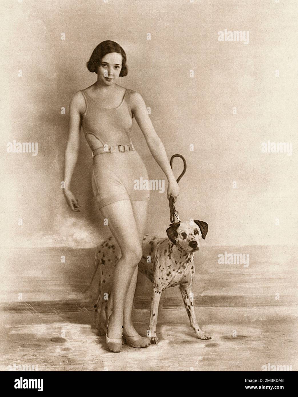 Jessie Matthews (1907-1981), britische Schauspielerin, Sängerin und Tänzerin, zu der Zeit, als sie in Ever Green im Adelphi Theatre in London auftrat. Sie trägt einen Badeanzug und wird von einem dalmatinischen Hund begleitet. Datum: 1931 Stockfoto