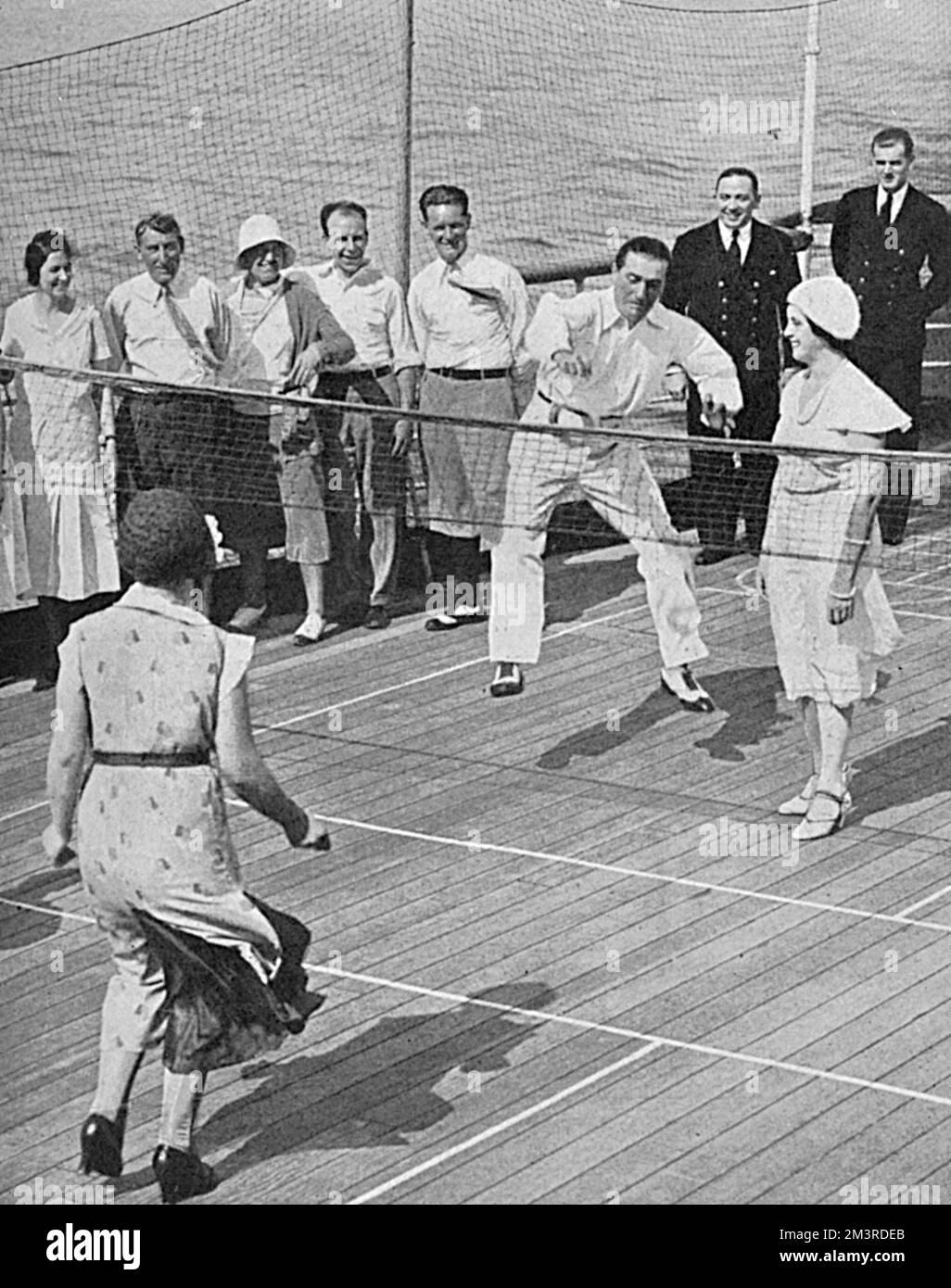 Die Passagiere spielen eine Form des Tennisspiels, gespielt von Hand mit einem Gummiring an Bord der Berengaria. Datum: 1931 Stockfoto
