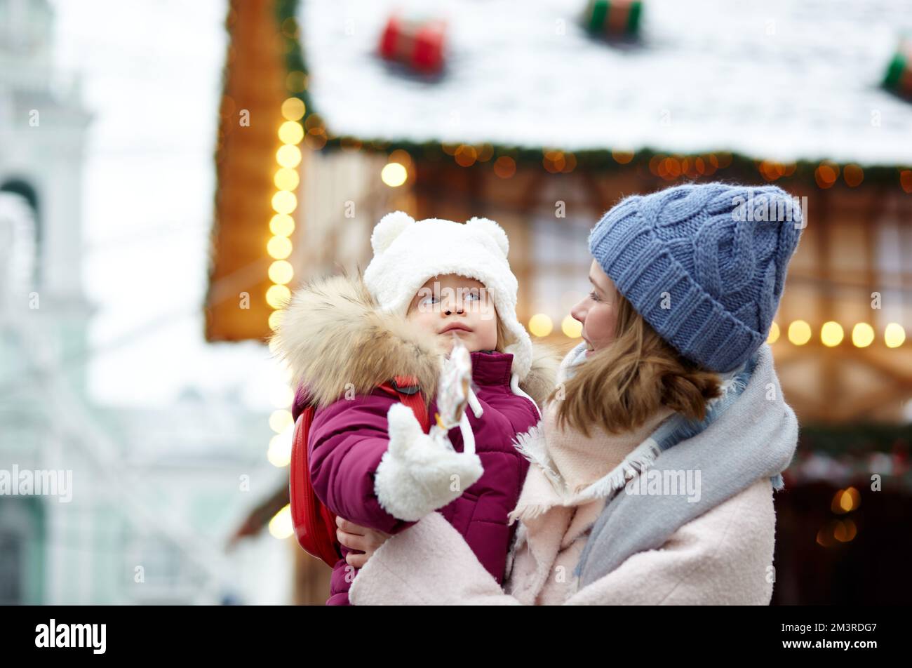 Mutter und Tochter laufen an Weihnachten und Neujahr durch die Stadt. Eltern und kleine Kinder haben Spaß im Freien Stockfoto