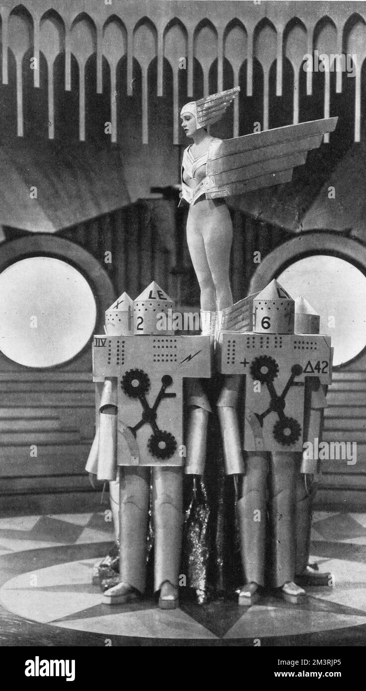 Corinne Griffith (1894-1979), Tänzerin und Schauspielerin, bekannt als die „Orchidee der Leinwand“, abgebildet in einer Szene aus dem Alexander Korda-Film „die Lilien des Feldes“. Sie spielt ein Showgirl, das an einer modernen Ballettmechanik teilnimmt und in silbernen Strumpfhosen die Figur von Speed auf einem Kühlerdeckel eines gigantischen Autos darstellte. Die Männer waren gekleidet, um Roboter zu repräsentieren. 1930 Stockfoto