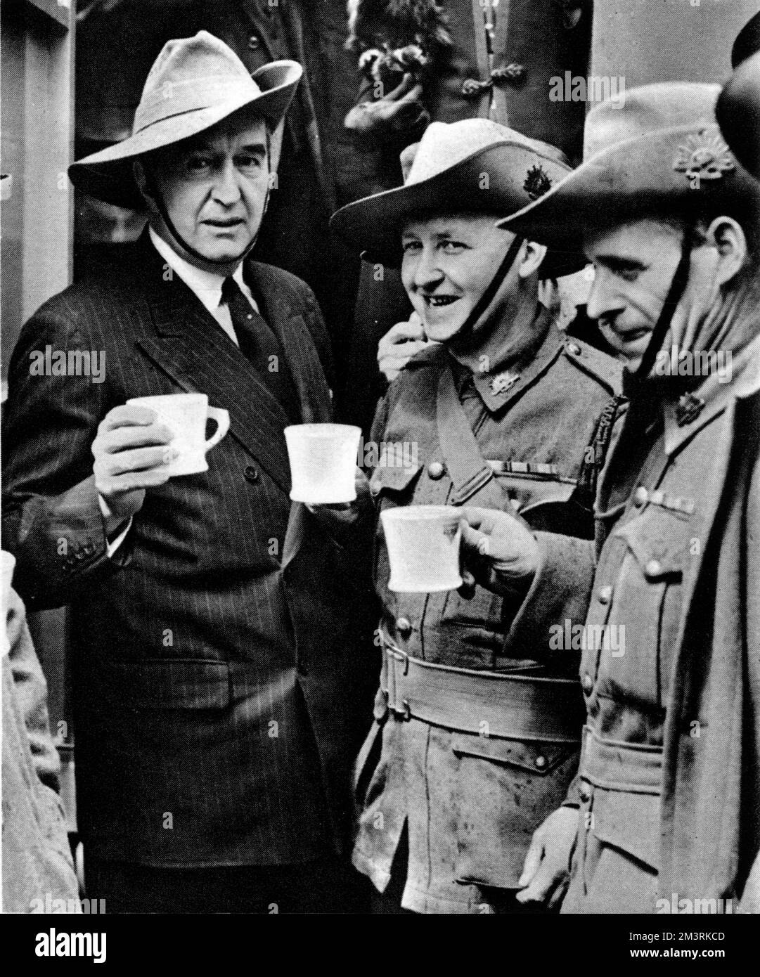 Der australische hohe Kommissar Stanley Bruce (links) steht neben zwei seiner Landsleute vor dem Strand Theatre in London. Alle drei probieren Tee aus einer neuen mobilen Kantine, die gerade in einer Zeremonie im Theater präsentiert wurde. 1940 Stockfoto