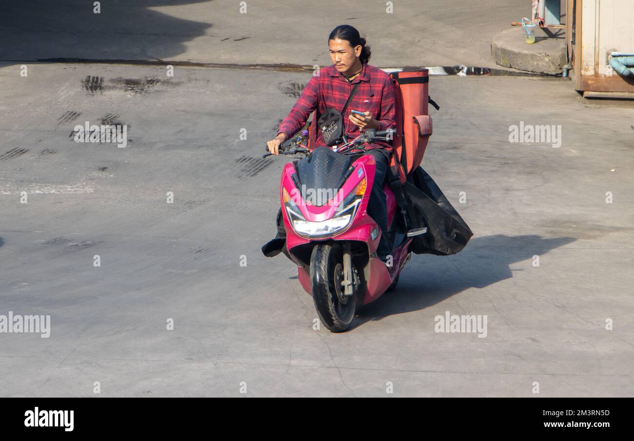SAMUT PRAKAN, THAILAND, Okt 19 2022, Ein Auslieferer fährt ein Motorrad mit Liefersäcken Stockfoto
