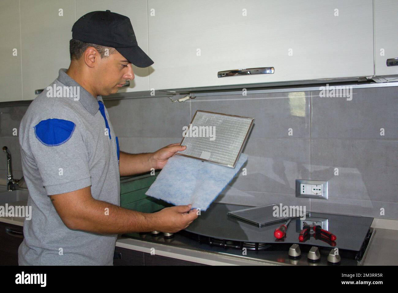 Bild eines Handwerkers, der den Filter der Küchenabzugshaube ersetzt. Machen Sie es selbst im Haus Stockfoto