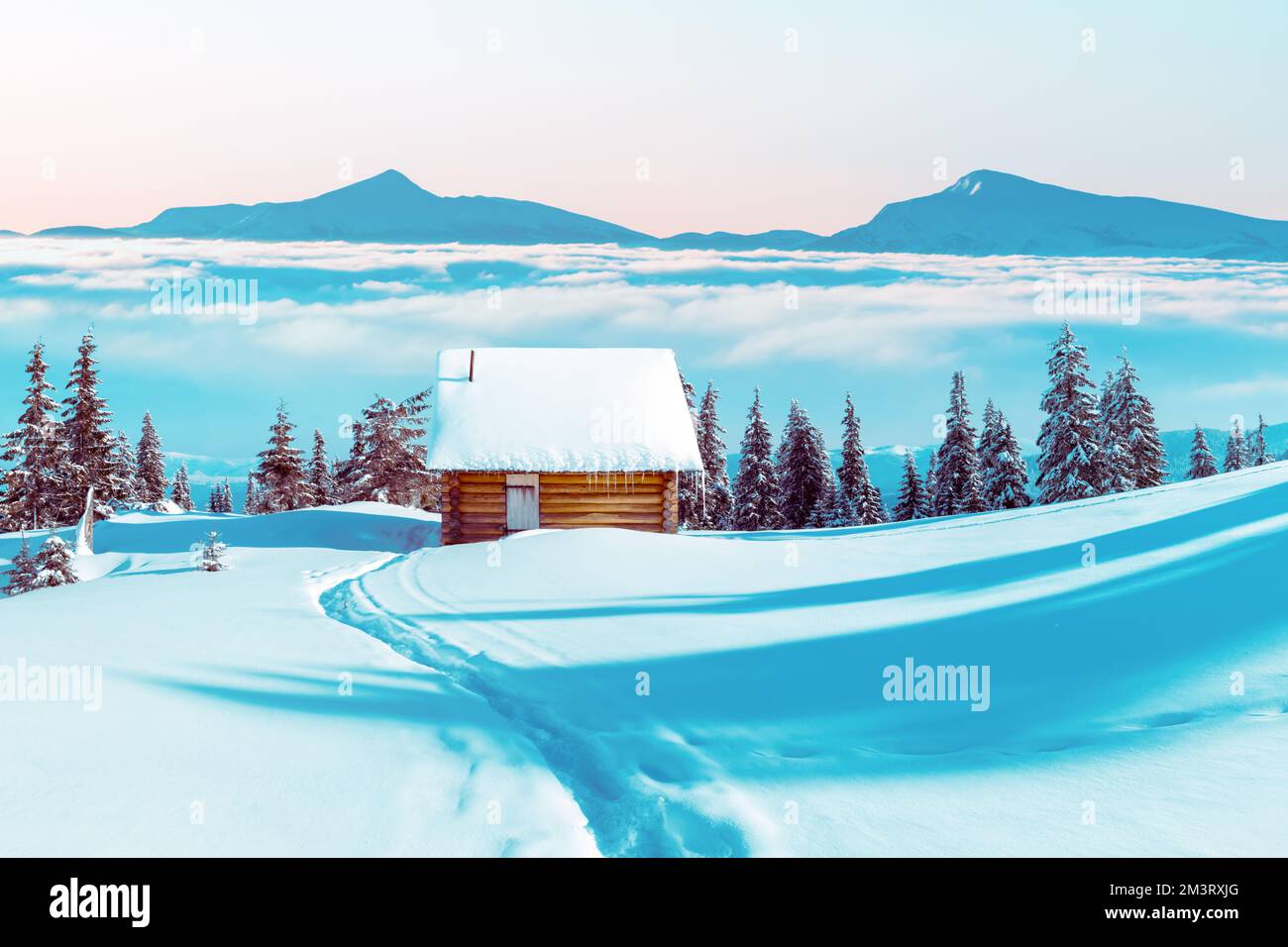 Fantastische Winterlandschaft mit Holzhaus und Berggipfeln im Nebel in schneebedeckten Bergen. Weihnachtskonzept. Karpaten Berg, Ukraine, Europa Stockfoto