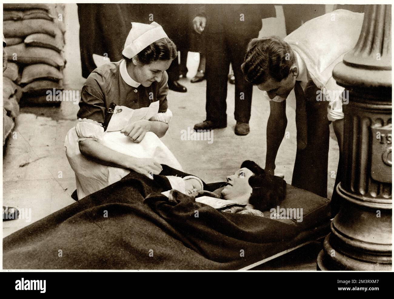 Eine Krankenschwester, die einer neuen Mutter und ihrem Baby ein paar Worte der Ermutigung gibt, während sie auf einer Trage liegt und darauf wartet, von einem Krankenwagen aus dem Westminster Krankenhaus evakuiert zu werden. Anfang September 1939, kurz nach dem Ausbruch des Krieges, wurden viele innerstädtische Krankenhäuser als Vorsichtsmaßnahme gegen Luftangriffe evakuiert. September 1939 Stockfoto