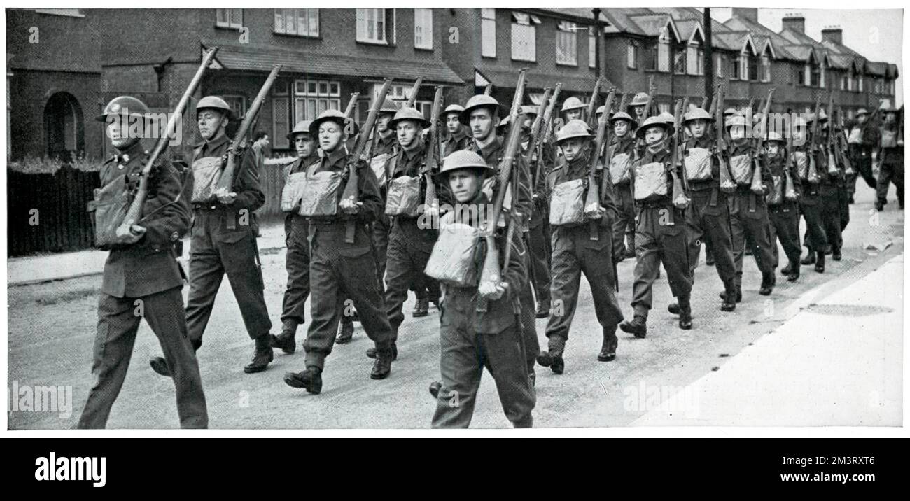 Männer in Uniform mit Waffen und Taschen um den Hals, die in Großbritannien marschieren. Die Sphäre äußert sich zu ihren neu entdeckten "Soldatenqualitäten" durch die Bewegung und frische Luft des militärischen Lebens. Datum: September 1939 Stockfoto