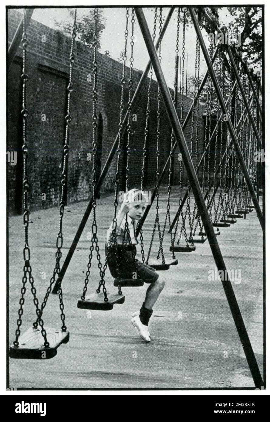 Foto eines Jungen auf einer Schaukel im Geraldine May Harmsworth Park. Nach der Evakuierung Tausender Kinder in den ersten Wochen nach Kriegsausbruch ist der Park leer. September 1939 Stockfoto