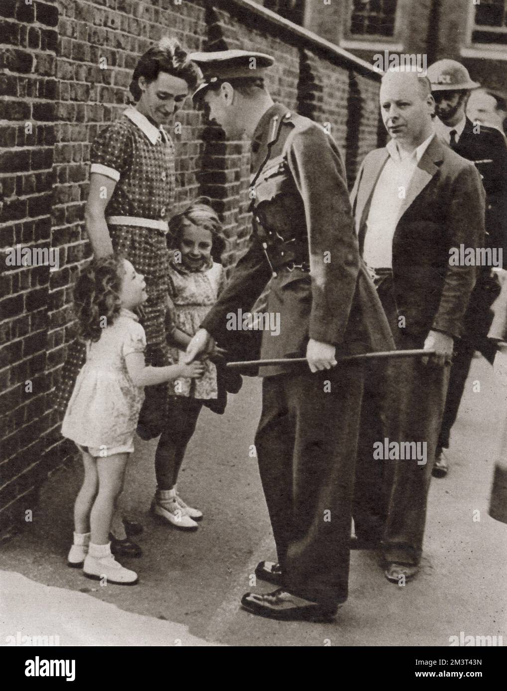 Der Besuch von König George VI im bombenzerstörten East End von London im September 1940: Händeschütteln mit der kleinen Tochter Joan Miles, der Hausmeisterin einer Schule, die bombardiert wurde. Stockfoto