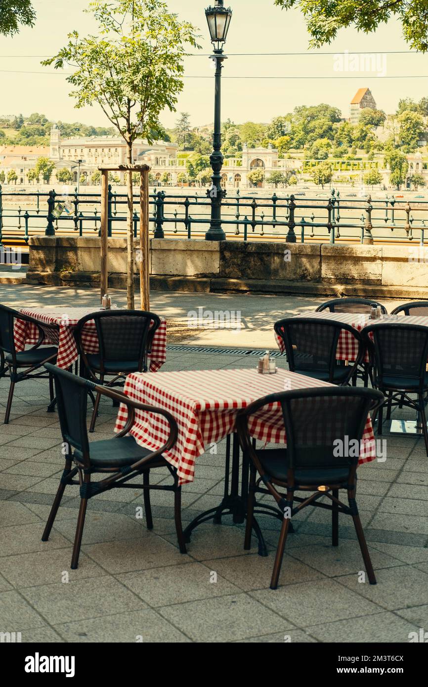 Vertikales Foto einiger Tische und Stühle von einer Café-Terrasse in Europa an einem Sommertag. Stockfoto